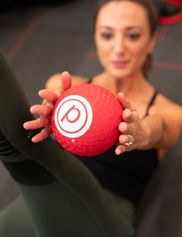 Person holding up red ball with Pure Barre logo